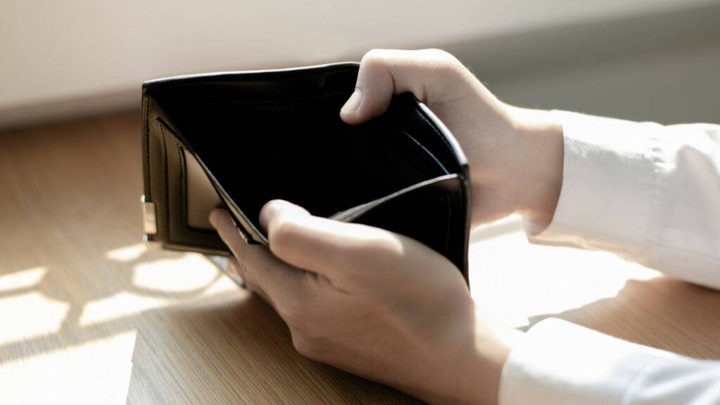Forensic Accounting A man holds a black wallet, forensically examining it on a table.