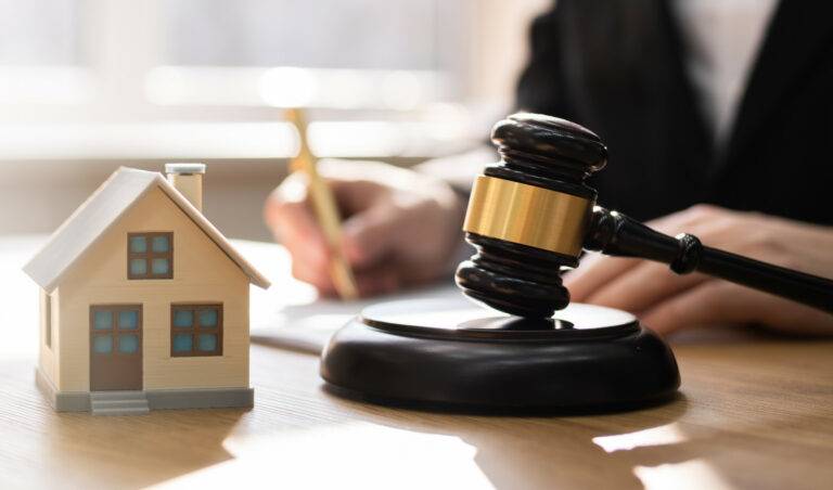 Forensic Accounting A woman demonstrating the role of a forensic accountant in ancillary relief services by showcasing a gavel and a house model on a table.